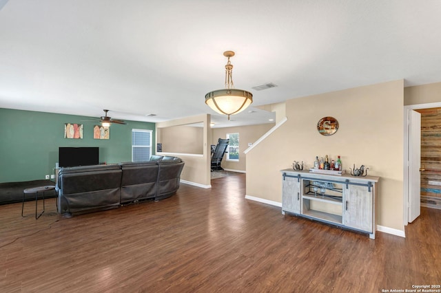 living room with dark wood-style flooring, visible vents, and baseboards