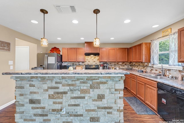 kitchen featuring black appliances, visible vents, a sink, and a center island