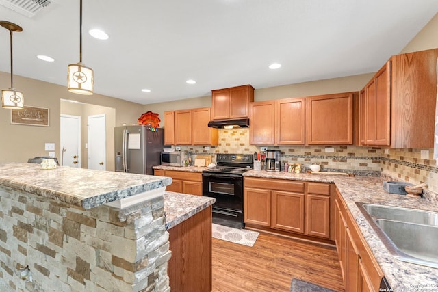 kitchen with light wood-style flooring, stainless steel appliances, a kitchen island, visible vents, and decorative light fixtures