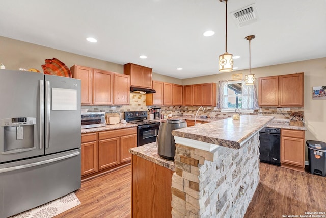 kitchen with visible vents, a center island, under cabinet range hood, light countertops, and black appliances