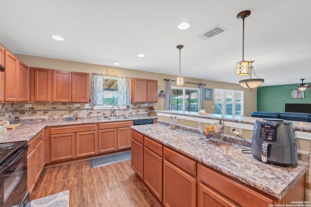 kitchen with dark wood-type flooring, a sink, visible vents, black appliances, and pendant lighting