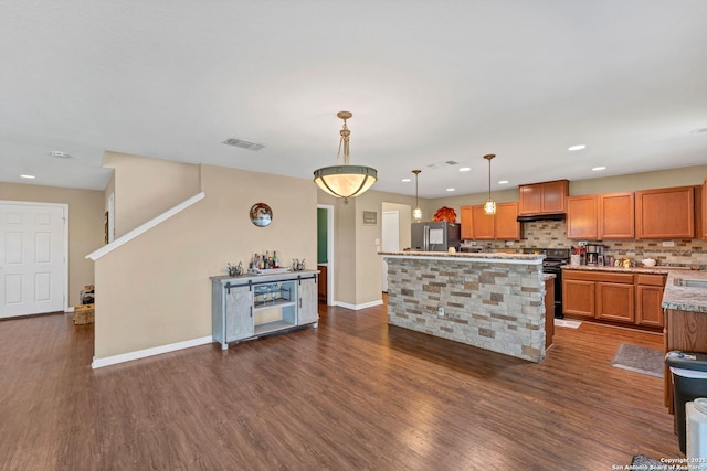 kitchen featuring pendant lighting, brown cabinets, stainless steel refrigerator with ice dispenser, light countertops, and black range with electric cooktop