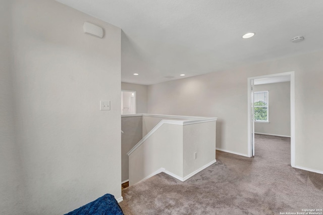 corridor with carpet, baseboards, an upstairs landing, and recessed lighting