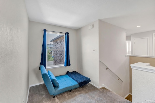 sitting room with carpet floors, baseboards, and an upstairs landing