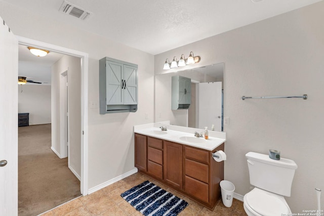 bathroom featuring toilet, double vanity, visible vents, and a sink