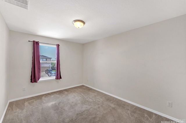 spare room with carpet, visible vents, and baseboards