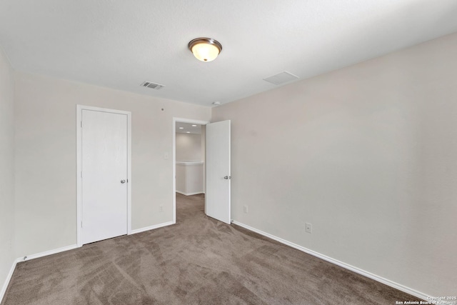 unfurnished bedroom featuring visible vents, dark carpet, and baseboards