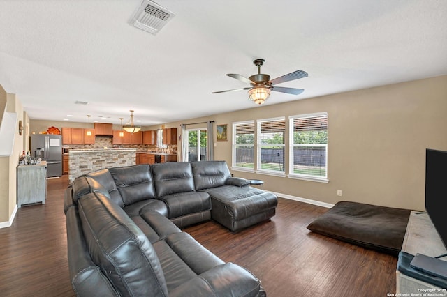 living room with baseboards, visible vents, dark wood finished floors, and a ceiling fan