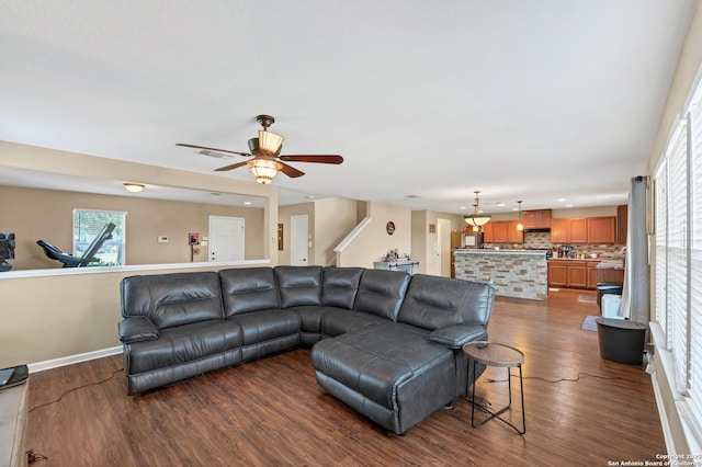 living room featuring dark wood-style flooring, visible vents, stairway, a ceiling fan, and baseboards