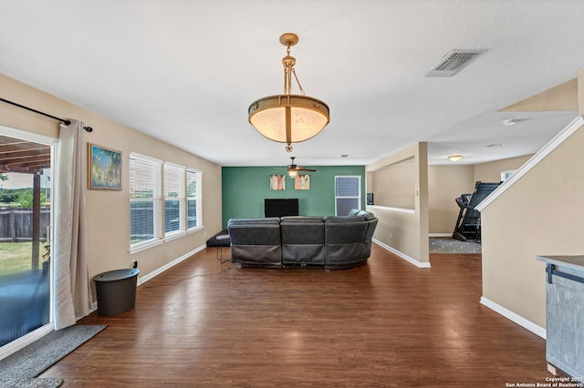 living area featuring dark wood-style flooring, visible vents, stairway, and baseboards