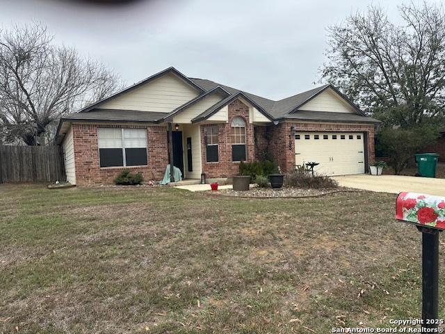 single story home featuring concrete driveway, brick siding, a front lawn, and an attached garage