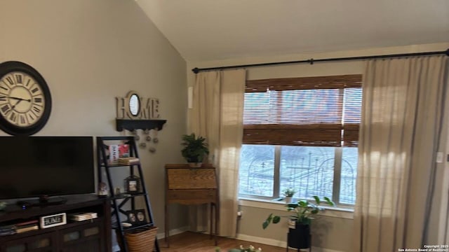 living area with baseboards and vaulted ceiling