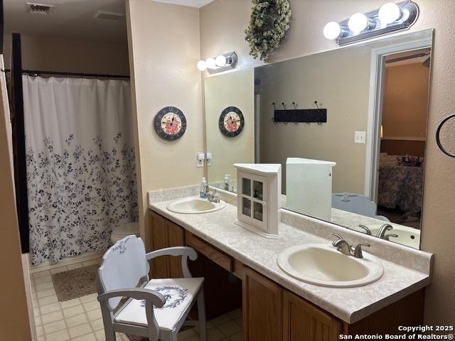 full bath with double vanity, curtained shower, a sink, and visible vents