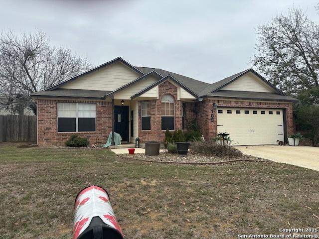 view of front of home featuring an attached garage, driveway, a front lawn, and brick siding