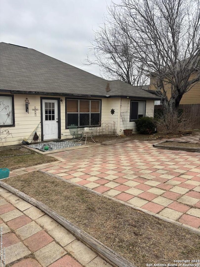 back of house featuring a shingled roof