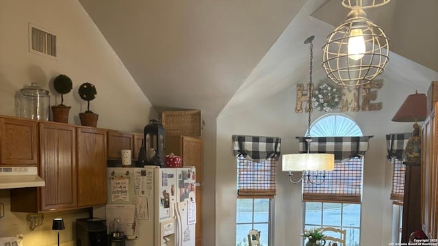 room details featuring white refrigerator with ice dispenser, brown cabinetry, visible vents, and under cabinet range hood