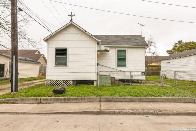 view of front facade with a front yard, roof with shingles, and fence