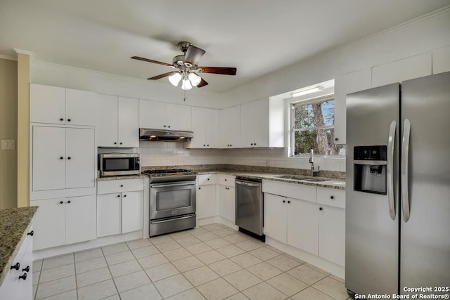 kitchen featuring tasteful backsplash, appliances with stainless steel finishes, white cabinets, a sink, and under cabinet range hood