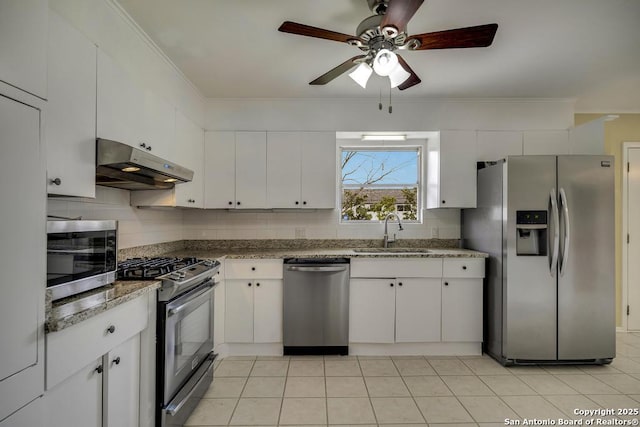 kitchen with stainless steel appliances, tasteful backsplash, white cabinets, a sink, and under cabinet range hood