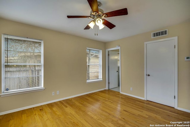 spare room with baseboards, a ceiling fan, visible vents, and light wood-style floors