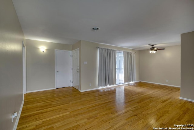 unfurnished room with light wood finished floors, baseboards, visible vents, and a ceiling fan