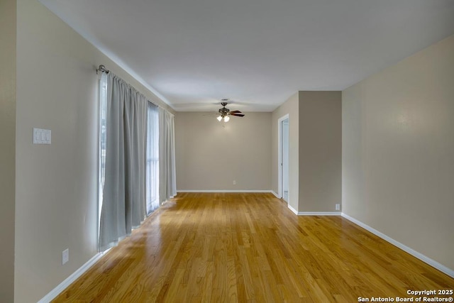 spare room with ceiling fan, light wood-style flooring, and baseboards