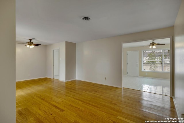 unfurnished room featuring a ceiling fan, visible vents, baseboards, and wood finished floors