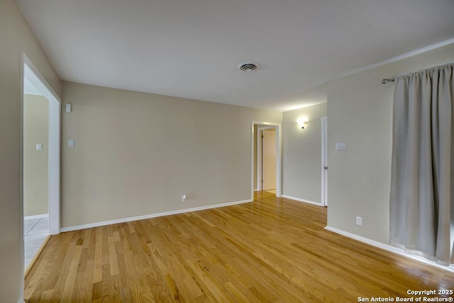 spare room featuring light wood-style flooring, visible vents, and baseboards