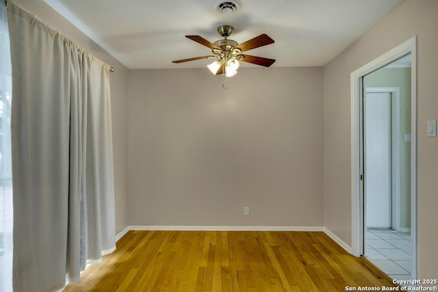 unfurnished room with a ceiling fan, light wood-style flooring, visible vents, and baseboards