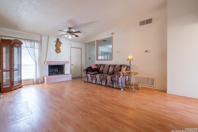 living area featuring light wood-style flooring, a high end fireplace, and visible vents