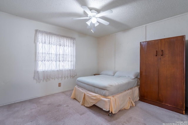 bedroom featuring a textured ceiling, ceiling fan, and light carpet