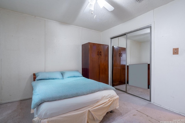 bedroom with light carpet, a textured ceiling, a ceiling fan, and a closet