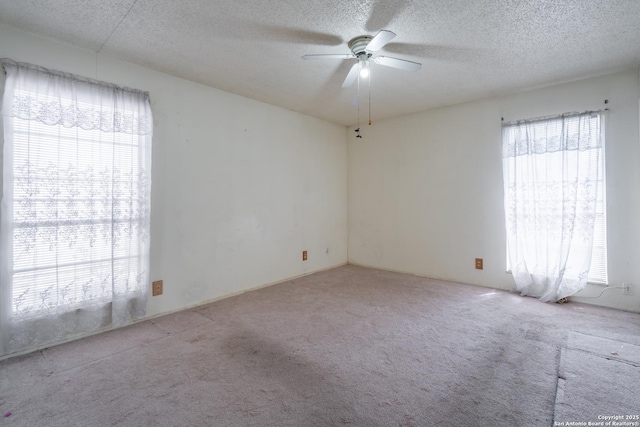 carpeted empty room with plenty of natural light, ceiling fan, and a textured ceiling