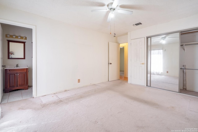 unfurnished bedroom featuring light carpet, a closet, visible vents, and connected bathroom