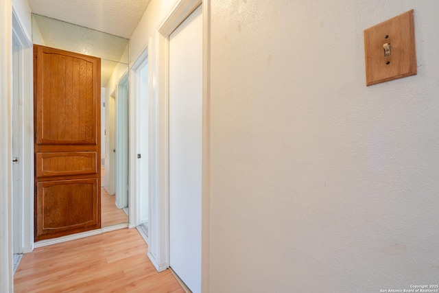 hall featuring a textured ceiling and light wood-style flooring