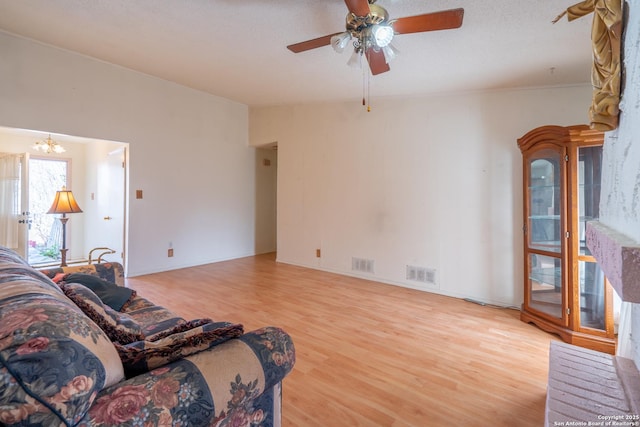 living area featuring light wood-style floors, visible vents, and ceiling fan with notable chandelier