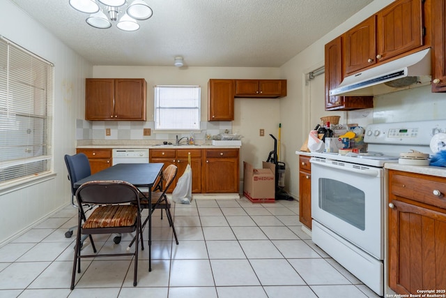 kitchen featuring light countertops, white appliances, brown cabinets, and under cabinet range hood