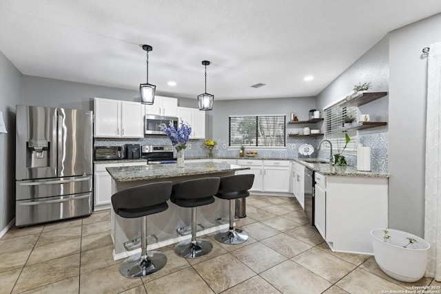 kitchen featuring white cabinets, a kitchen island, stainless steel appliances, and a sink