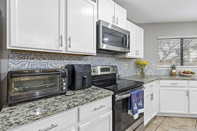 kitchen featuring a toaster, white cabinetry, stainless steel appliances, and light stone counters