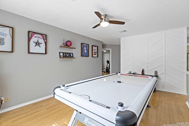 recreation room with a ceiling fan, visible vents, baseboards, and wood finished floors