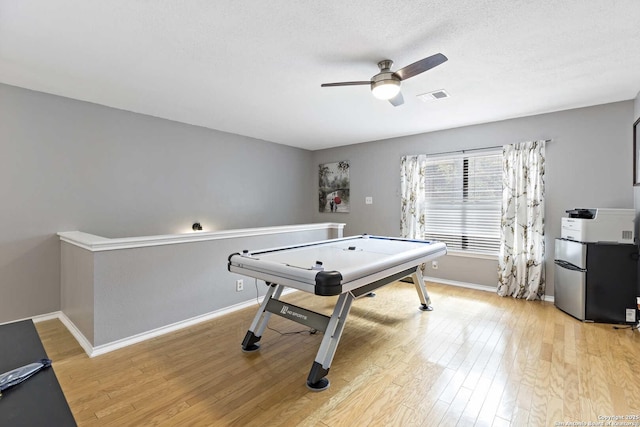 game room featuring visible vents, light wood-style floors, ceiling fan, a textured ceiling, and baseboards