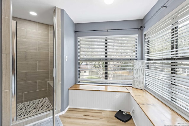 full bath with wood finished floors, a wealth of natural light, and a shower stall