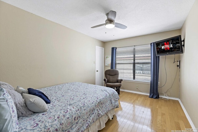 bedroom with a textured ceiling, ceiling fan, wood finished floors, and baseboards