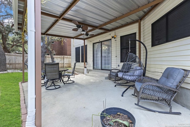 view of patio with ceiling fan, outdoor dining space, and fence