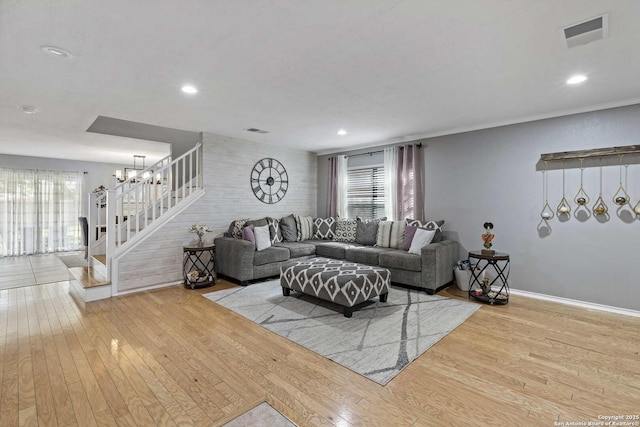 living area with stairway, baseboards, visible vents, and light wood-style floors