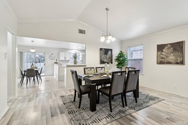 dining space with light wood-style flooring, a notable chandelier, visible vents, vaulted ceiling, and crown molding