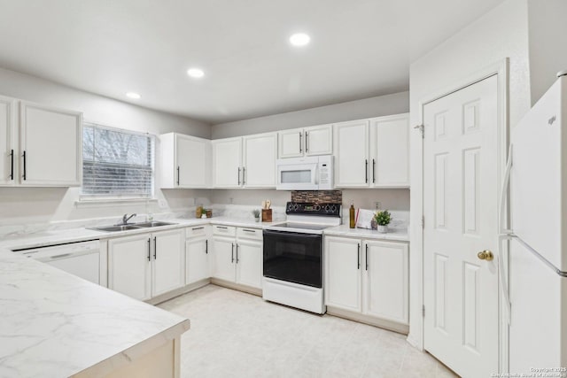 kitchen with white appliances, white cabinetry, and a sink