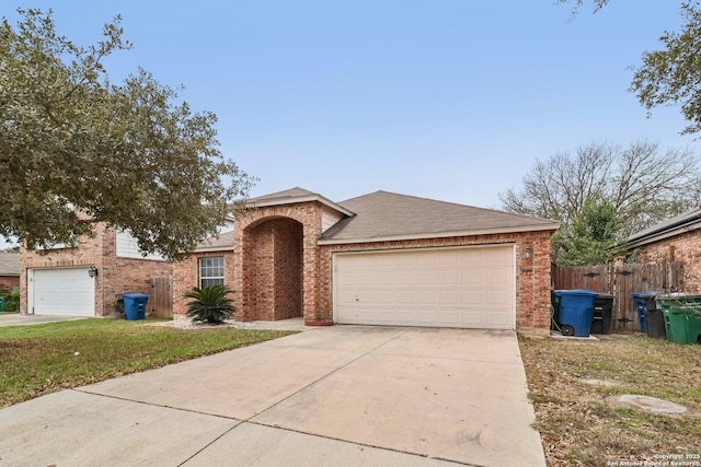 ranch-style home featuring driveway, brick siding, an attached garage, and fence