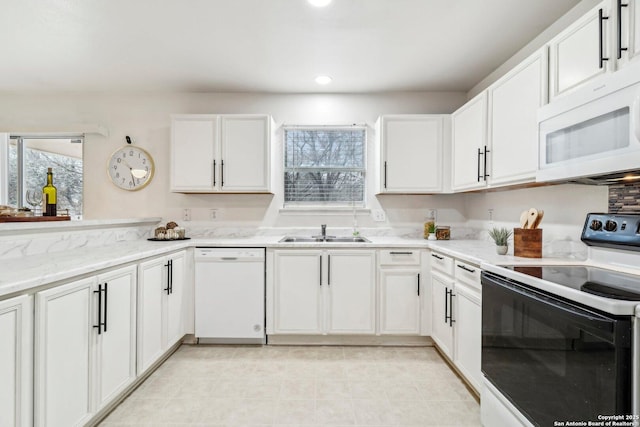 kitchen featuring light stone countertops, white appliances, white cabinets, and a sink