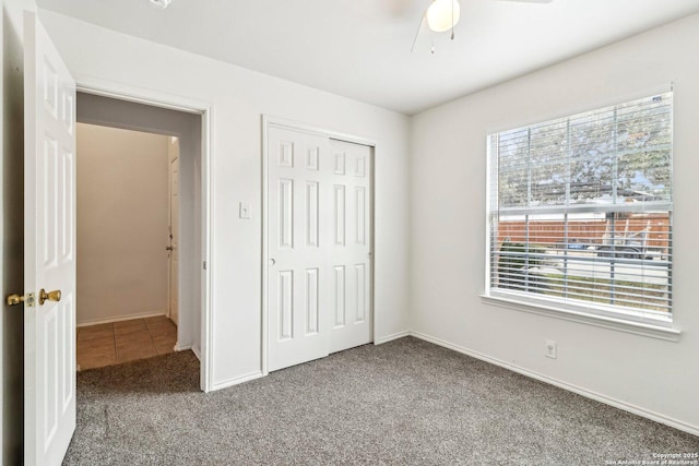 unfurnished bedroom with carpet floors, ceiling fan, baseboards, and a closet